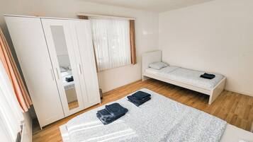 A bedroom with a bed, a wardrobe, and a window with curtains.