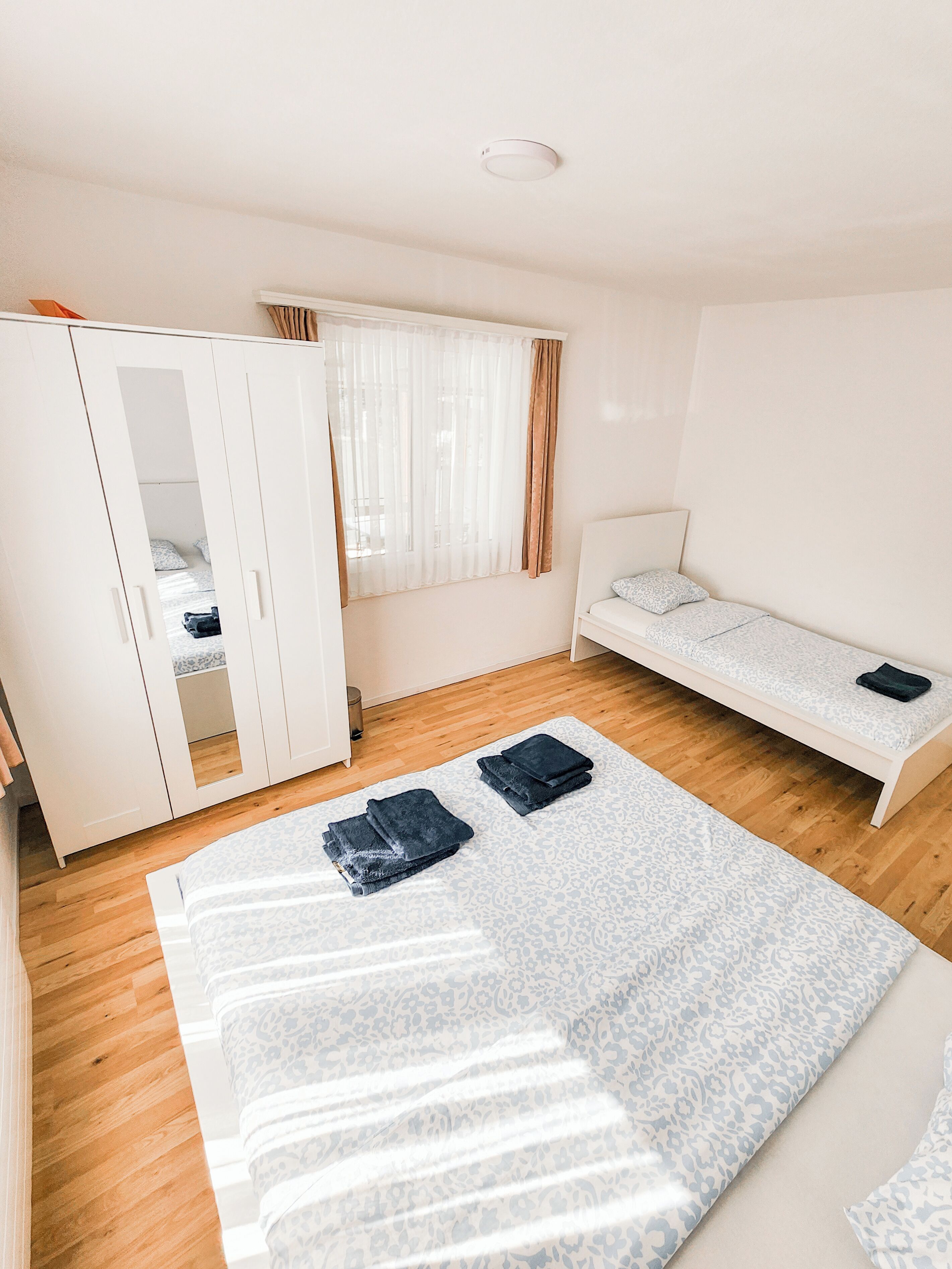 A room with a bed, a wardrobe, and a window with curtains.