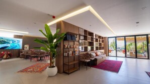 Un salon moderne avec une grande télévision, une bibliothèque, un canapé et un coin repas.