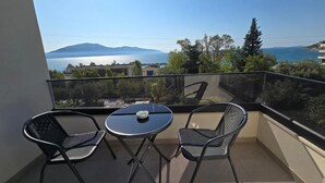 A balcony with two chairs and a small table, overlooking a scenic view of the sea and distant mountains. - White Hill Radhime (Orikum)