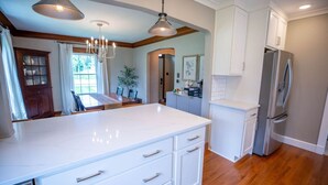 A modern kitchen with a large island, white cabinetry, and a stainless steel refrigerator. - Game Room/Foosball/3BD/Families/Coffee Bar/Poker (Des Moines)