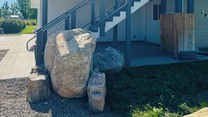 A modern two-story house with a balcony, a staircase, and large rocks in the foreground. - Entire rental unit. 5 guests. Large private deck. 2 beds. 1 sofa bed. 1 bath. (Belgrade)