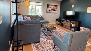 A living room with a sofa, armchair, coffee table, TV, and a plant. - Entire rental unit. 5 guests. Large private deck. 2 beds. 1 sofa bed. 1 bath. (Belgrade)