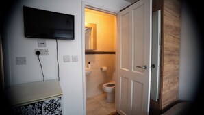 Ein Badezimmer mit Toilette, Waschbecken und einem an der Wand befestigten Fernseher.