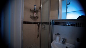 Ein Badezimmer mit Duschkabine aus Glas, einem weißen Waschbecken und einer Toilette.