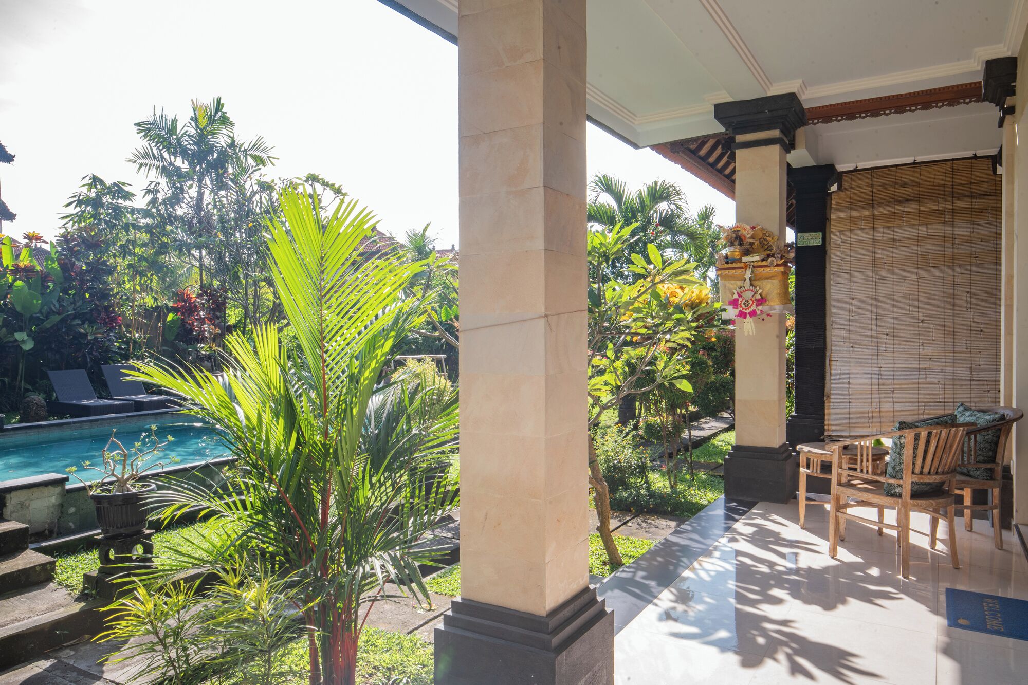 A poolside area with a view of a pool, surrounded by lush greenery and a wooden deck.