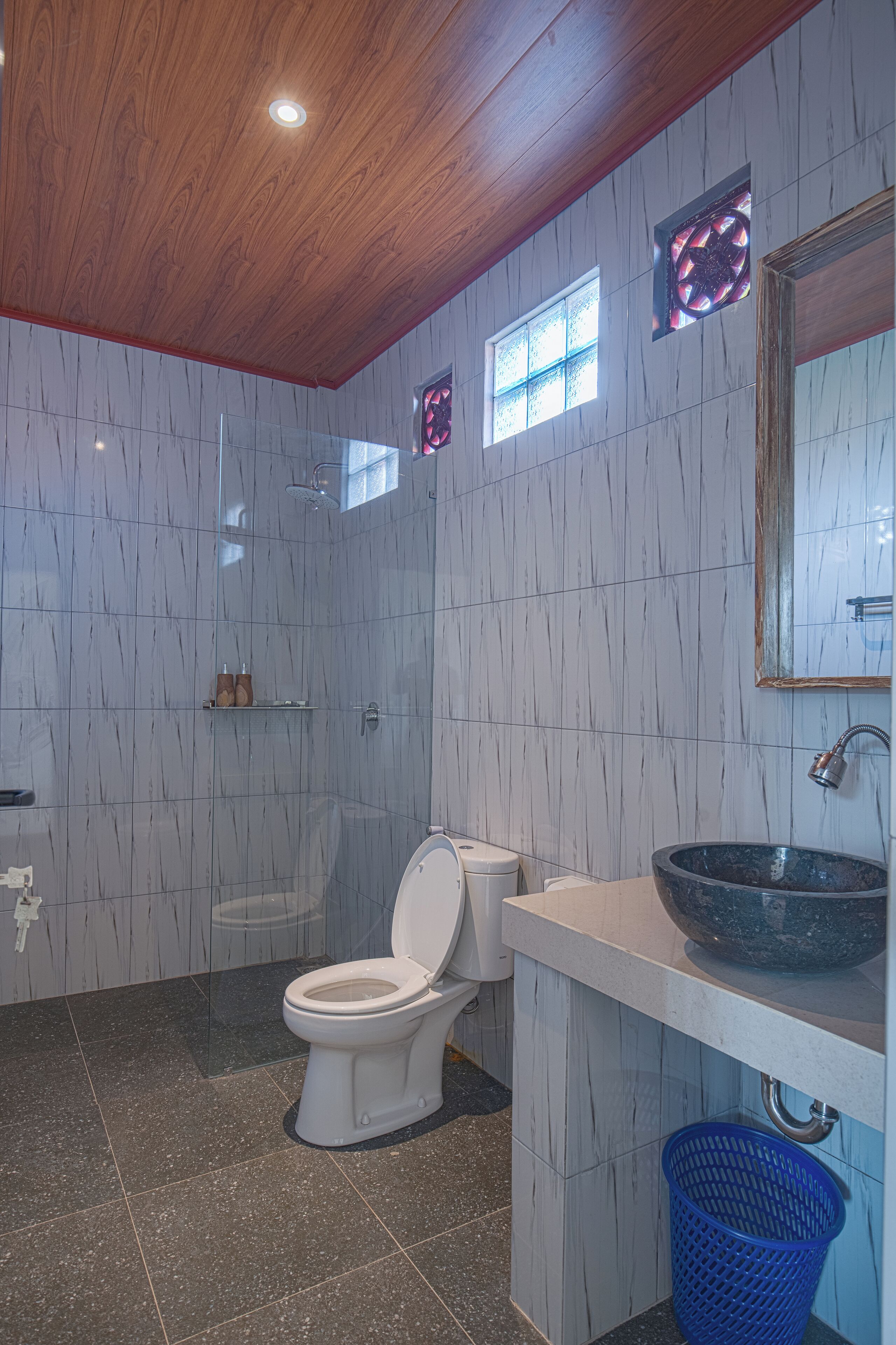 A bathroom with a toilet, a sink, a shower, and a blue basket.