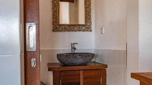 A bathroom with a wooden vanity, a large mirror, and a vessel sink. - Darsa House Ubud (Ubud)
