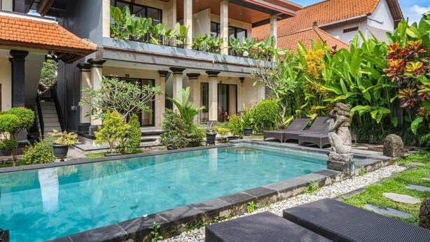 A swimming pool surrounded by lush greenery and outdoor seating. - Darsa House Ubud (Ubud)