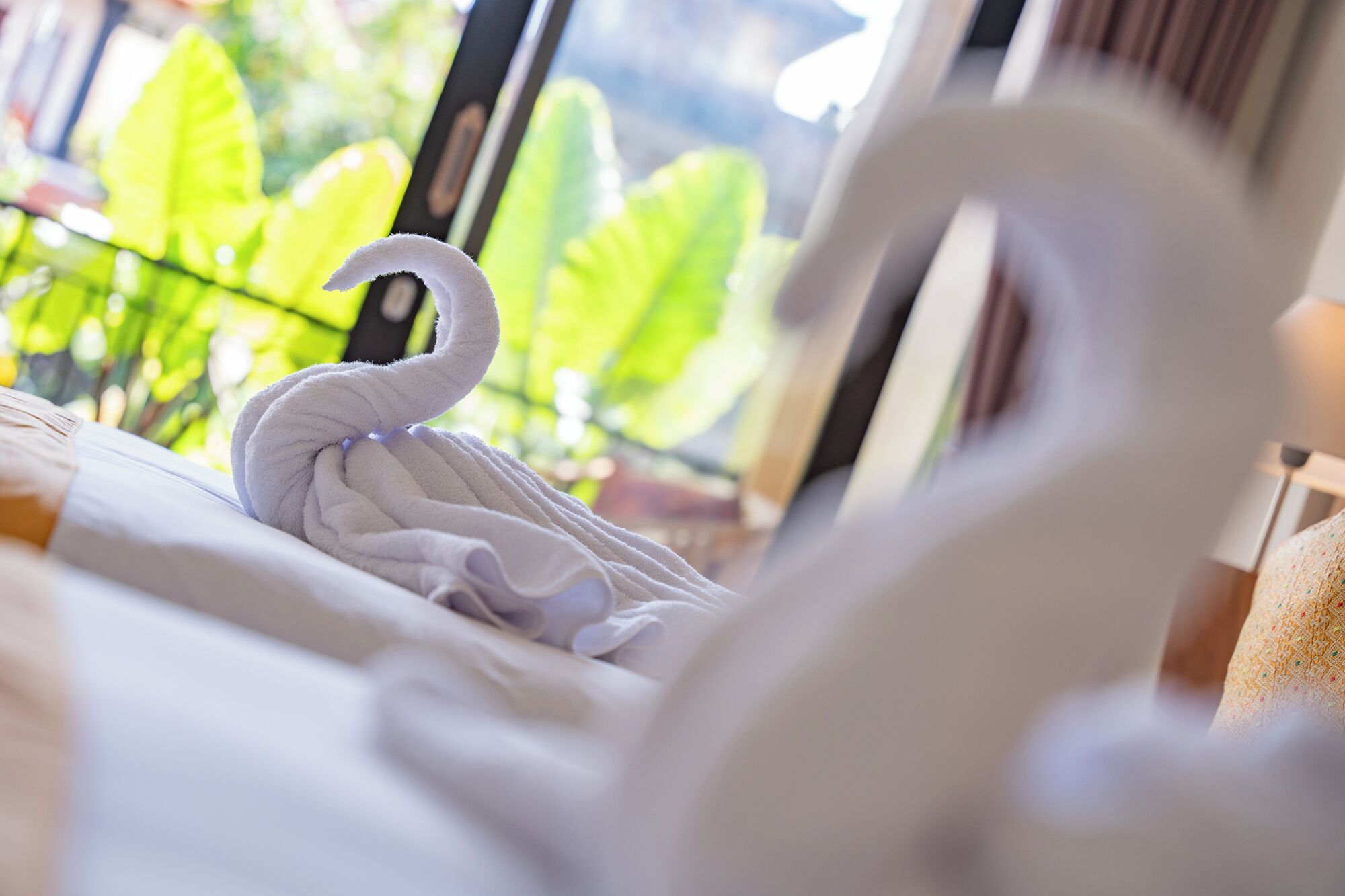 A bed with a white swan-shaped towel.