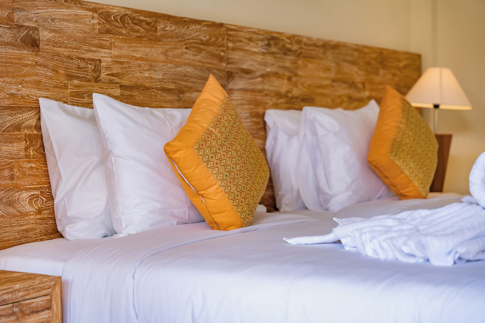 A bed with white bedding and two decorative pillows, one with a geometric pattern.