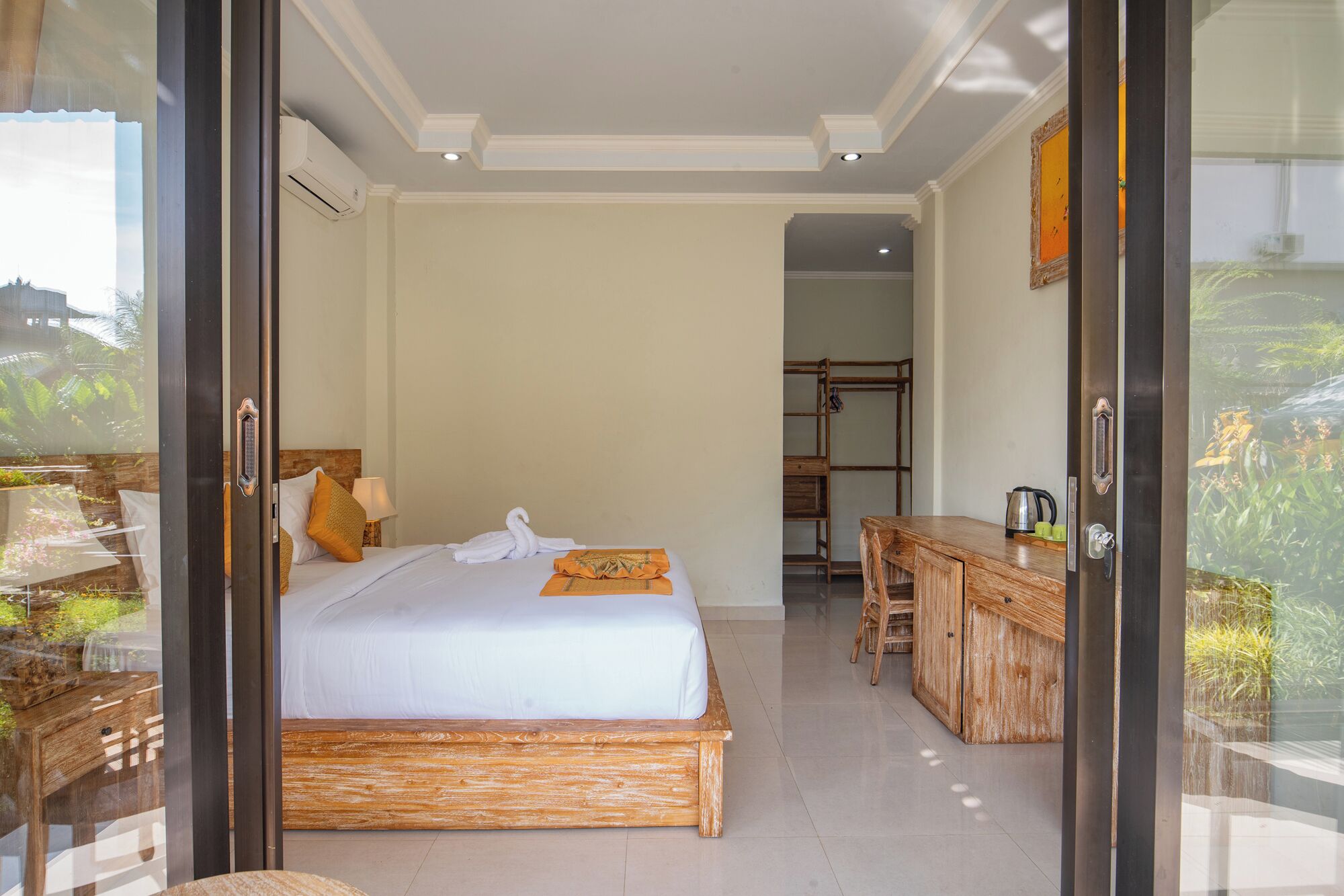 A modern hotel room with a large bed, a wooden desk, and a view of the outdoors.