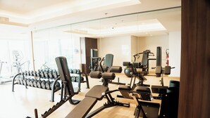 A gym with various exercise equipment, including treadmills, weight machines, and dumbbells. - Modern 1BR in J One Pool & Gym (Dubai)