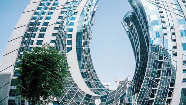 A modern skyscraper with a unique curved design and reflective glass facade. - Modern 1BR in J One Pool & Gym (Dubai)