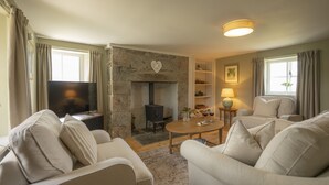 A living room with a stone fireplace, a television, and a sofa.