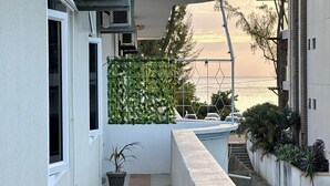 A balcony with a view of the sea, a potted plant, and a hanging light fixture. - Kazafibi B4 - Steps away from the beach (Flic en Flac)