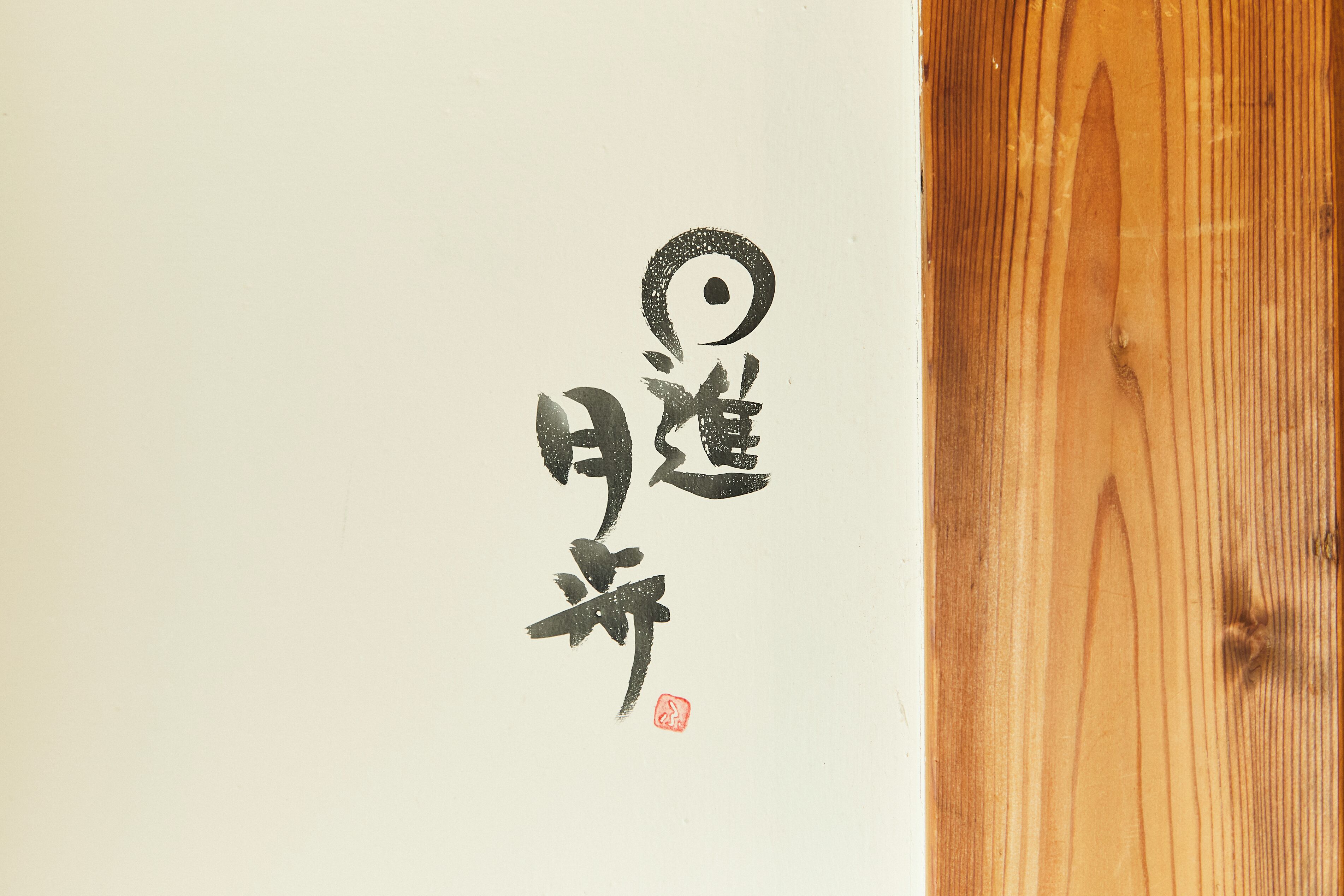 A piece of calligraphy on a white background with a wooden panel to the right.