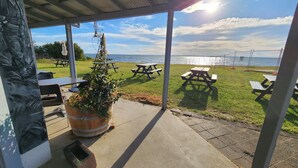 Un espace extérieur abrité, équipé de tables de pique-nique et offrant une vue sur la mer.