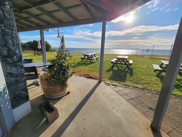A covered outdoor area with picnic tables and a view of the sea.