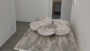 Une pièce avec une table en bois, un tableau accroché au mur et une porte donnant sur une autre pièce.
