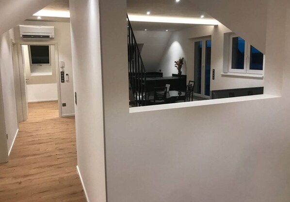 Un intérieur moderne avec un plancher en bois, un escalier, un coin repas et une cuisine.