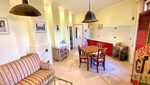 A cozy living room with a sofa, a dining table with chairs, and a kitchen area with a red cabinet. - Bed and Dreams (Florence)