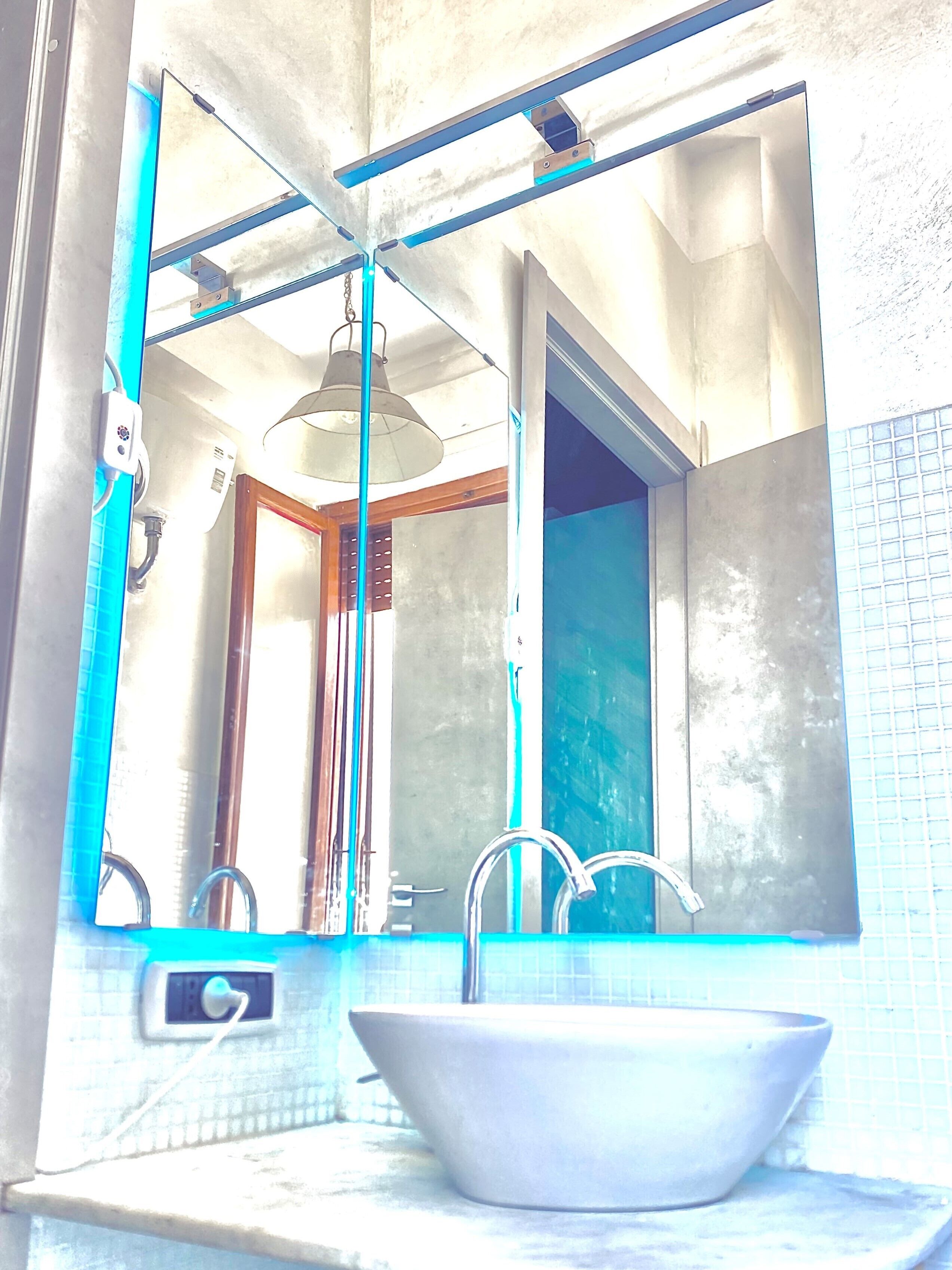 A bathroom with a large mirror, a white sink, and a blue-tiled wall.