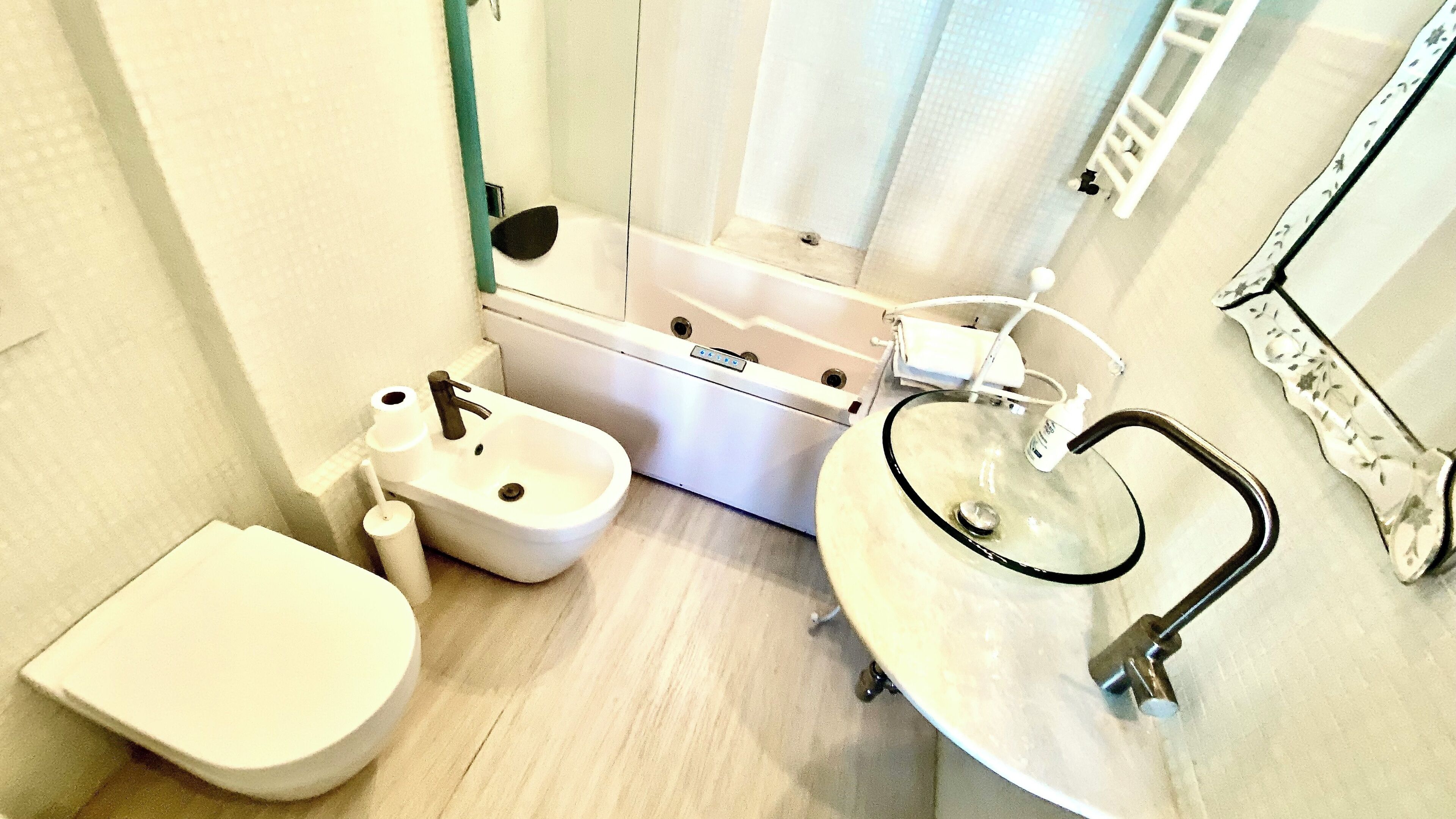 A bathroom with a toilet, a bidet, a sink with a glass basin, and a mirror.