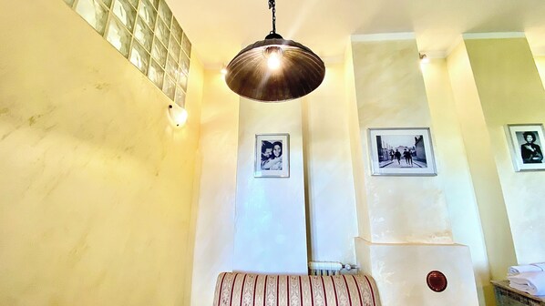 Una habitación con una lámpara colgante, un banco y cuadros en la pared.
