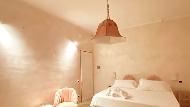 A bedroom with a bed, a chair, and a hanging light fixture. - Bed and Dreams (Florence)
