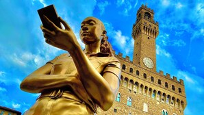 A statue of a woman holding a smartphone with a clock tower in the background. - Bed and Dreams (Florence)