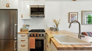 Una cocina compacta con un refrigerador de acero inoxidable, un horno empotrado y una encimera de madera.