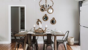 Un comedor con una mesa de madera, cuatro sillas y una araña.
