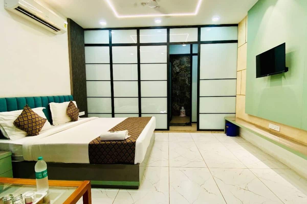 A modern hotel room with a bed, bedside table, and a TV mounted on the wall.
