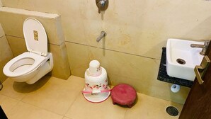 A bathroom with a toilet, a bidet, a sink, and a trash bin.