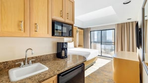 A hotel room with a kitchen area, a bed, a coffee maker, and a large window with a view. - Polo Towers Las Vegas (Las Vegas)