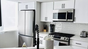 Una cocina moderna con gabinetes blancos, electrodomésticos de acero inoxidable, una estufa a gas y un microondas.