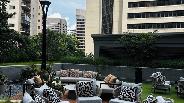 Terraza en la azotea con mobiliario exterior, rodeada de edificios altos.