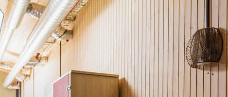 A wooden-paneled room with a large red storage unit, a small plant on top, and a woven wall decoration.
