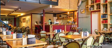 A restaurant with multiple dining tables and chairs, a bar area, and a loft space with a view.