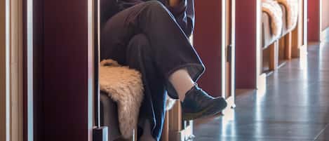 A person sitting on a bench in a hallway with wooden paneling and red doors, reading a book titled 'Living Earth'.