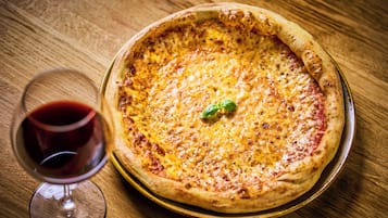 A pizza on a round metal tray on a wooden table.