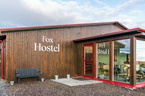A wooden building with a sign reading 'Fox Hostel' and a bench outside. - The Fox Hostel (Hrífunesvegur)