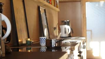 A kitchen with a stove, a kettle, and a cup on the counter.