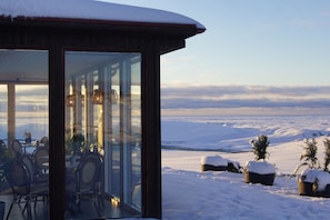 Un paysage enneigé avec un bâtiment doté de grandes fenêtres en verre et d’une terrasse.