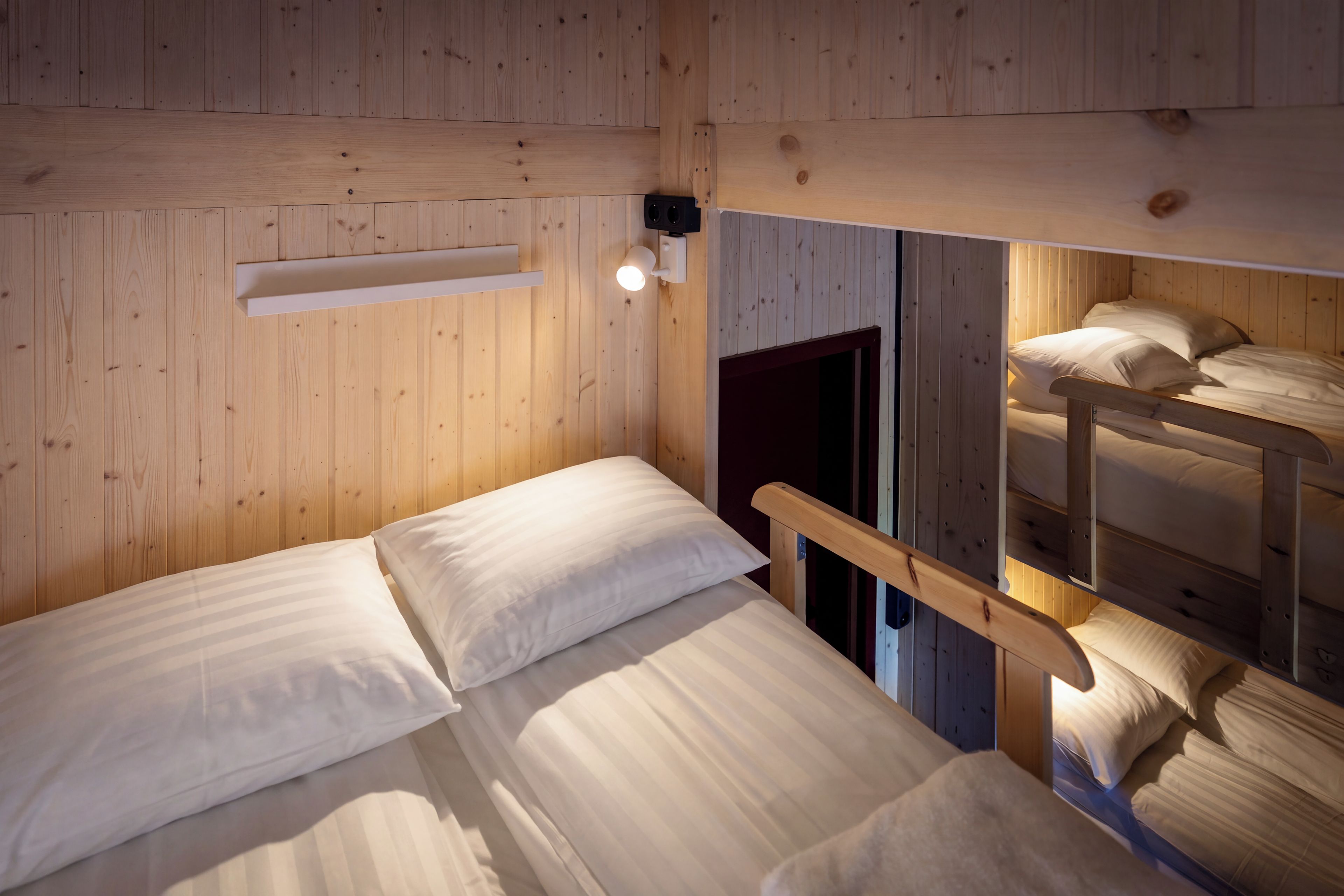 Une chambre avec un lit superposé, des murs en bois et une petite table de chevet.