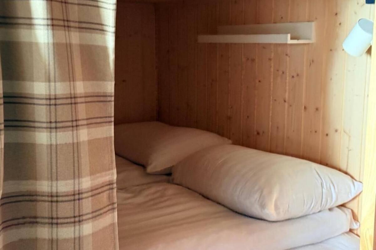 Ein Zimmer mit Holzboden, einem Bett, einer Kopfteil und einer Wandleuchte.