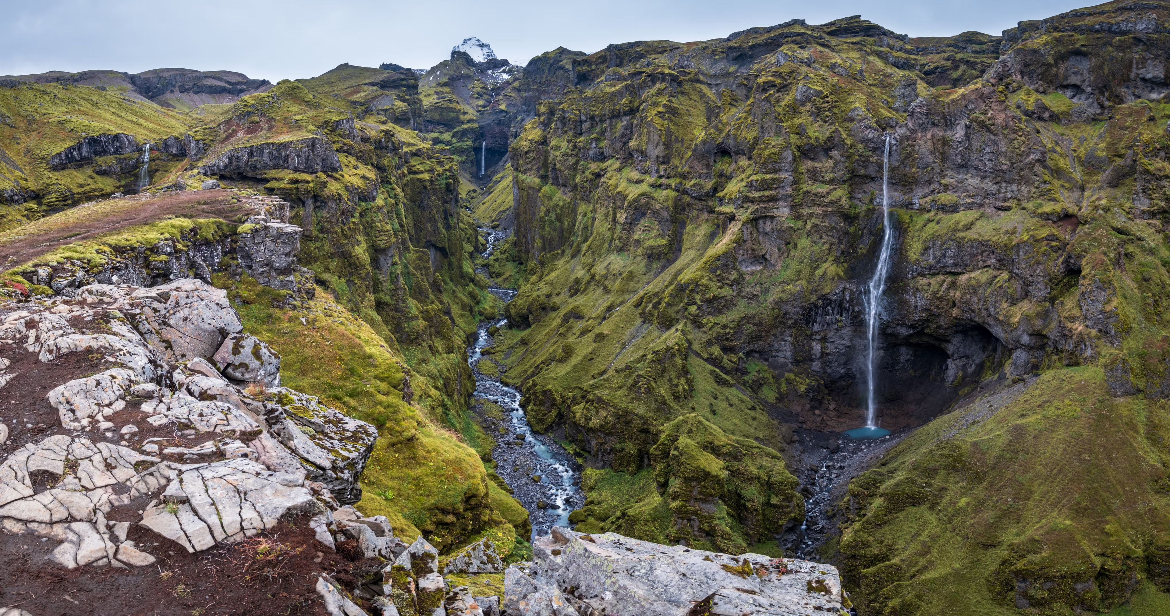 Un paisaje montañoso con múltiples cascadas y un río que atraviesa un valle.