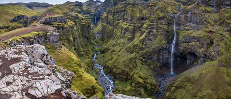 Un paisaje montañoso con múltiples cascadas y un río que atraviesa un valle.