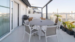 A rooftop terrace with a round table and chairs, a grill, and potted plants. - 2BR Penthouse Paradise w/ Jacuzzi & BBQ in Sliema (Sliema)